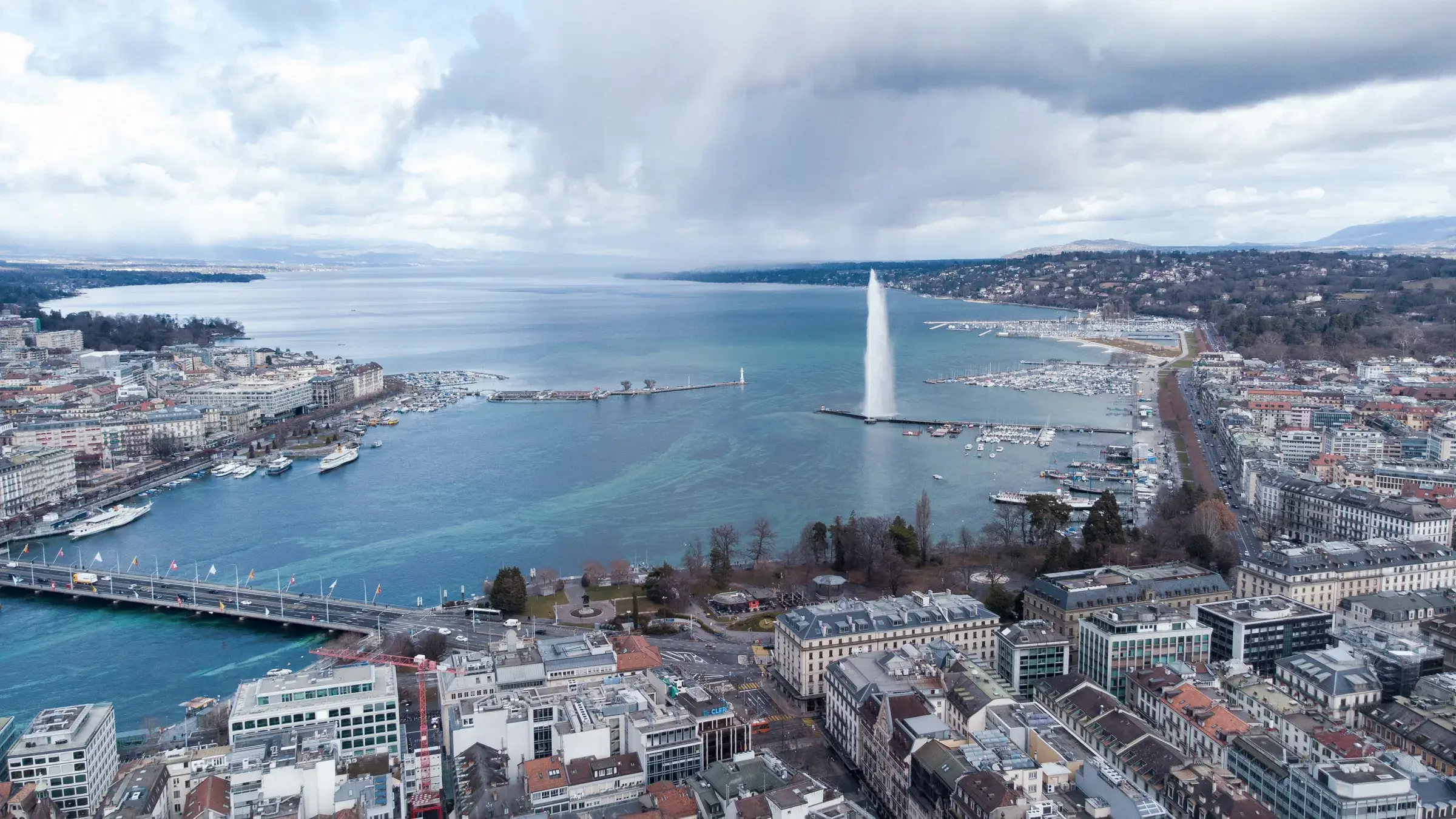 Vue aérienne de la rade de Genève, du jet d'eau et du pont du Mont-Blanc sous un ciel d'orage